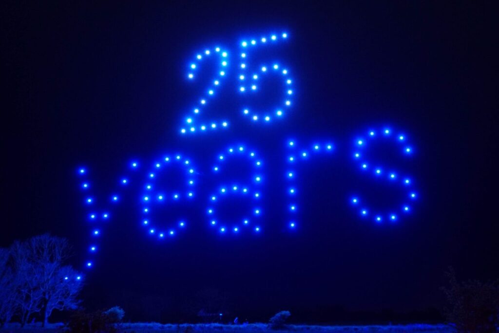 Blue lights in the night sky form the words "25 years.